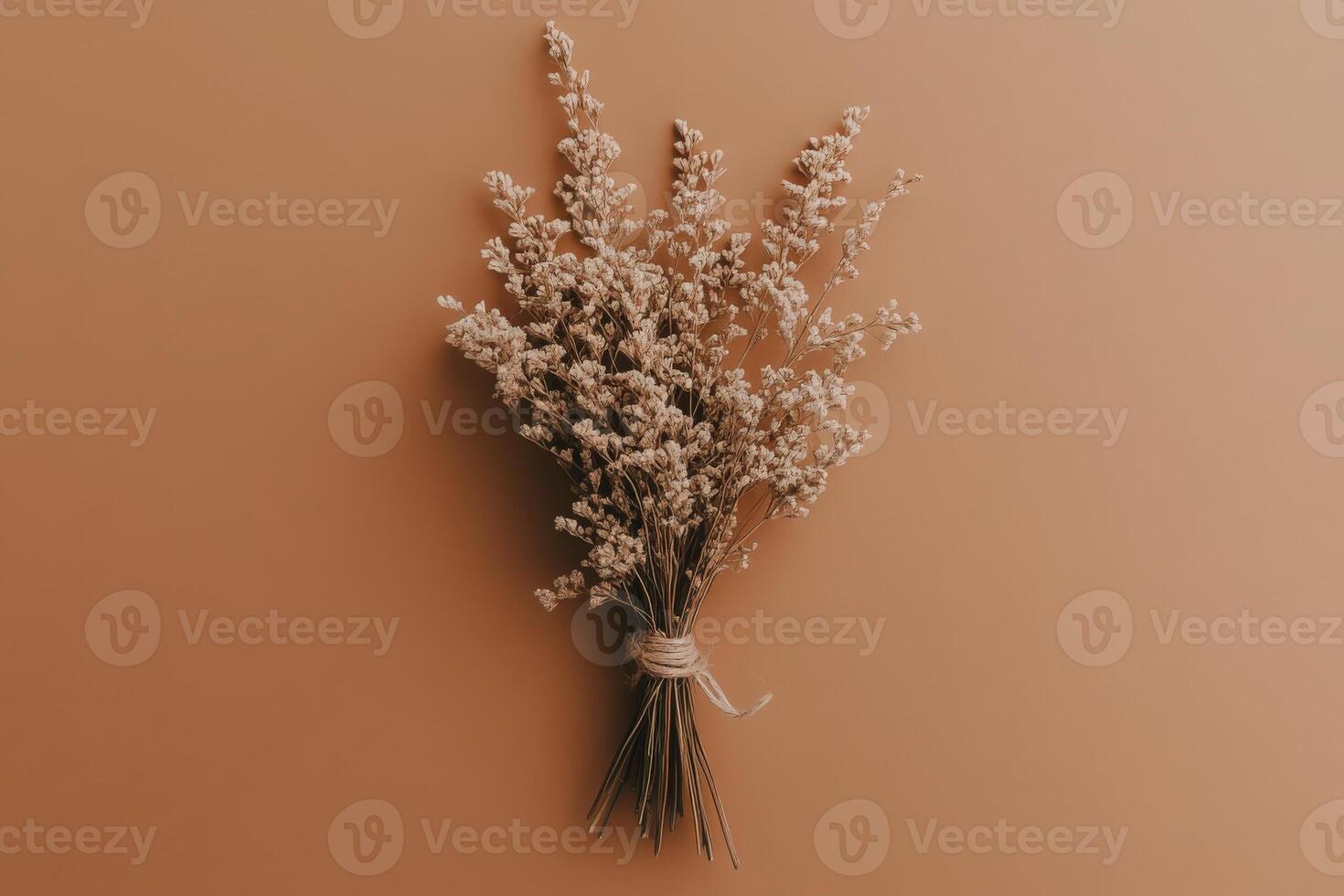 An elegant bundle of dried herbs, intricately bound, evokes a sense of rustic charm. The warm backdrop enhances the natural beauty and earthy tones, creating a serene atmosphere. photo