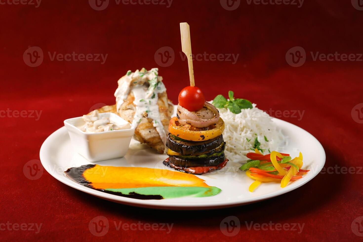 Grilled lemon chicken rice with grilled vegetables and served with a creamy sauce served in plate isolated on red background side view of arabic food photo