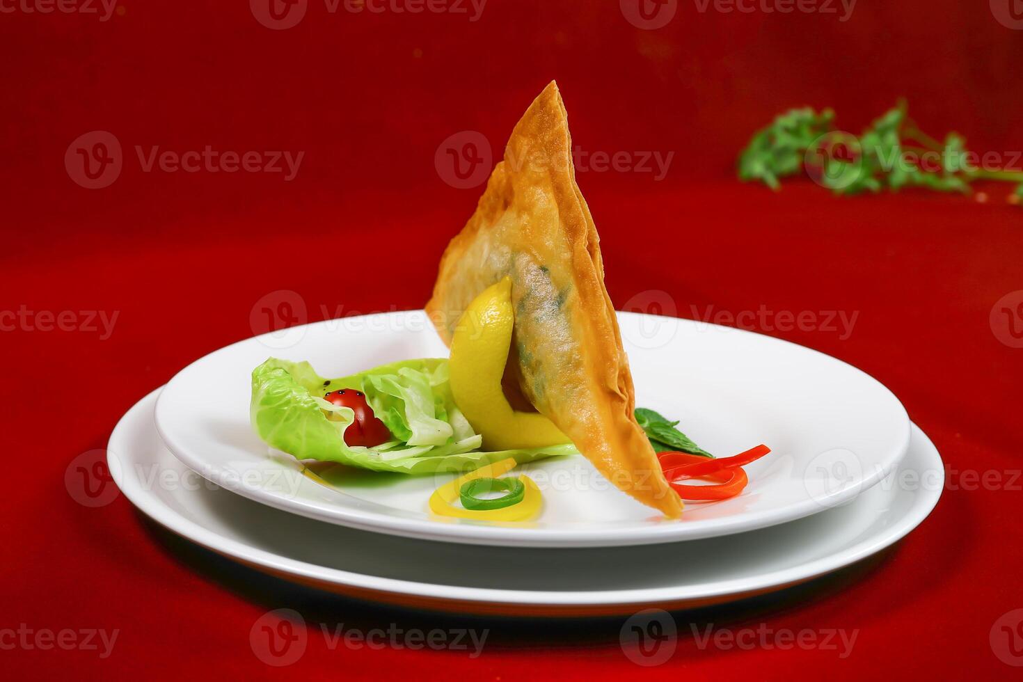 Crispy and Spicy Samosa filled with vegetable and meat with salad served in plate isolated on red background side view of ramadan food photo