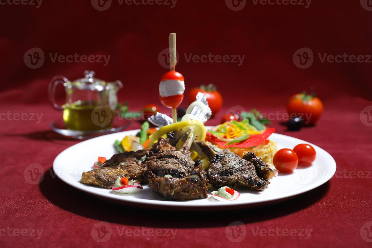 Grilled Lamb Chops with Mediterranean vegetables, including roasted tomatoes, zucchini, and red peppers served in plate isolated on red background side view of arabic food photo