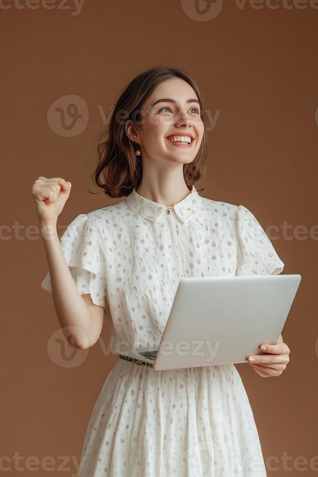 woman is pictured holding a laptop computer and smiling while gesturing with her left hand photo