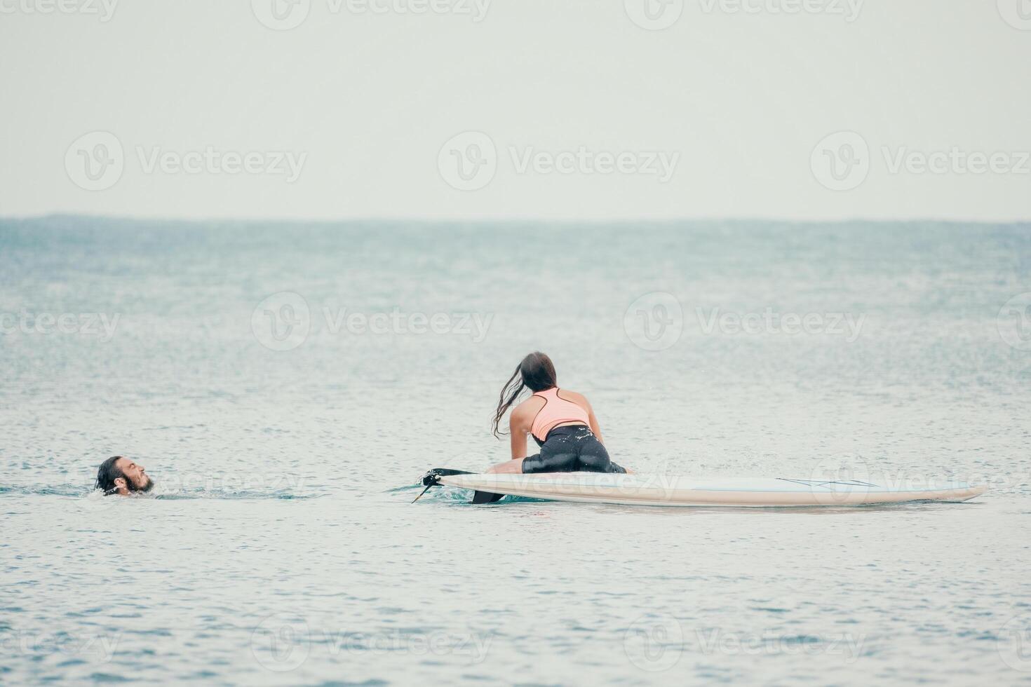 Sea woman and man on sup. Silhouette of happy young woman and man, surfing on SUP board, confident paddling through water surface. Idyllic sunset. Active lifestyle at sea or river. photo