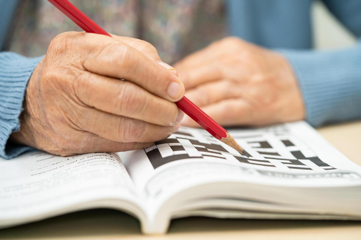 Asian elderly woman playing sudoku puzzle game to practice for dementia prevention. photo