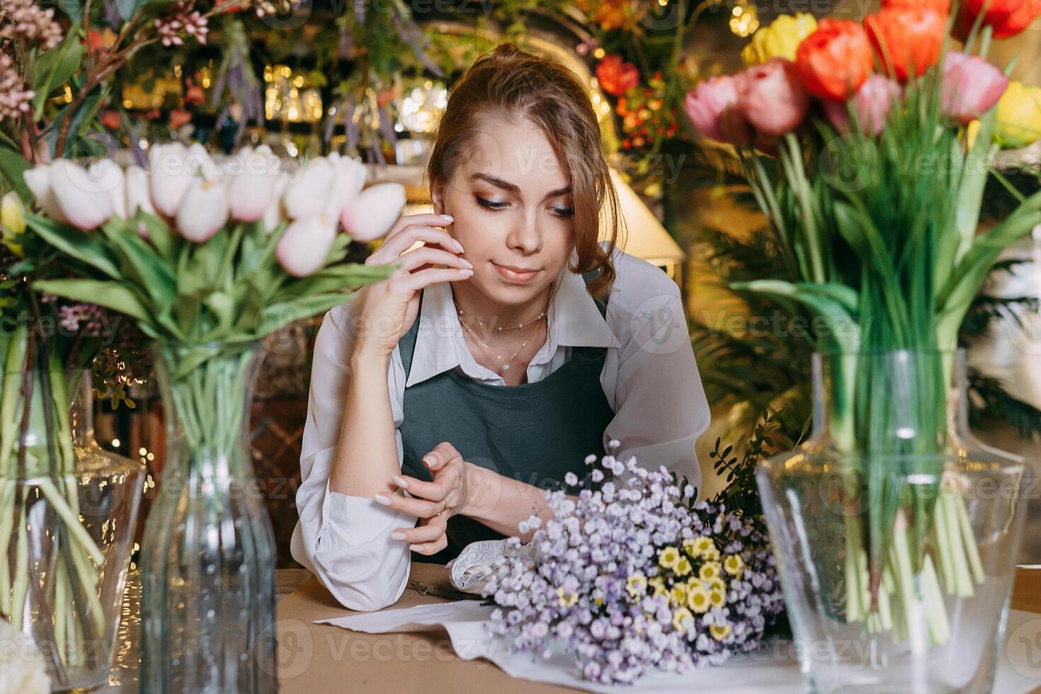A woman in her florist shop collects bouquets of flowers. The concept of a small business. Bouquets of tulips for the holiday on March 8. photo