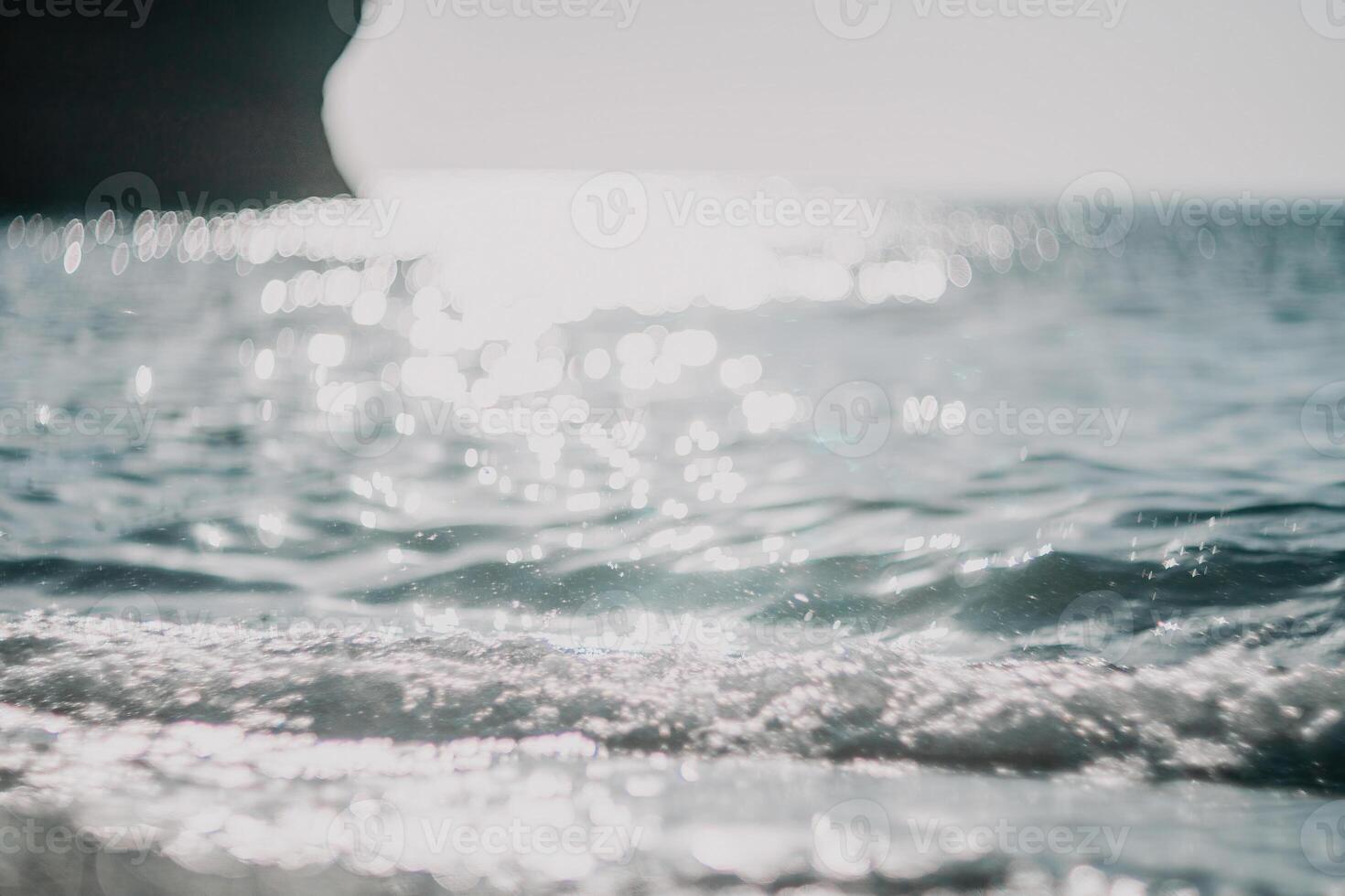 Blurred golden sea at sunset. The sun reflects and sparkles on the waves with bokeh, illuminating the golden sea. Holiday recreation concept. Abstract nautical summer ocean sunset nature background. photo