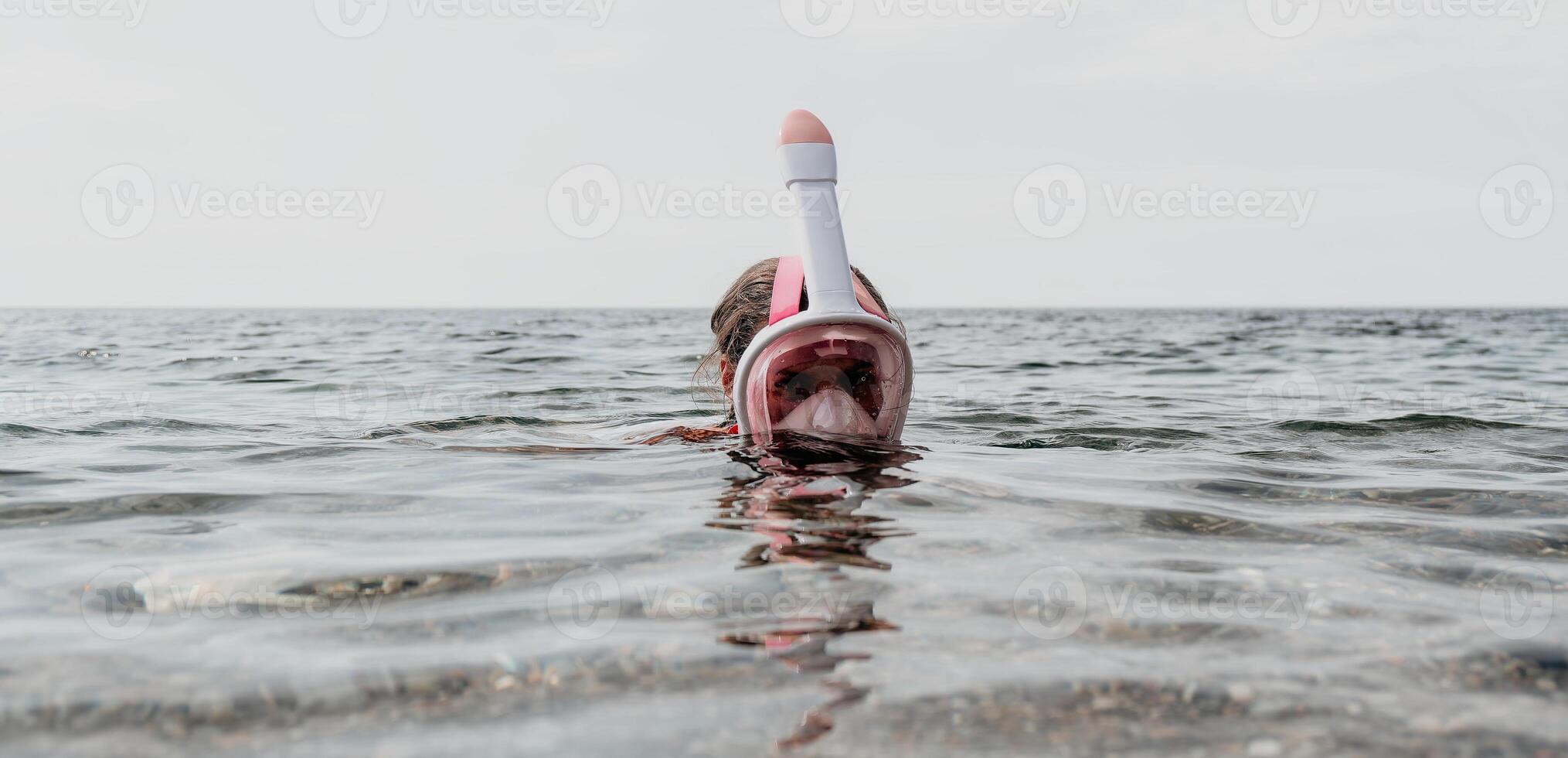 Young happy woman in white bikini and wearing pink mask gets ready for sea snorkeling. Positive smiling woman relaxing and enjoying water activities with family summer travel holidays vacation on sea. photo