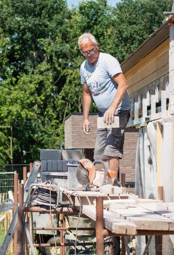 the bricklayer makes the facade of the house from gray bricks with cement and plaster at the construction site. High quality photo