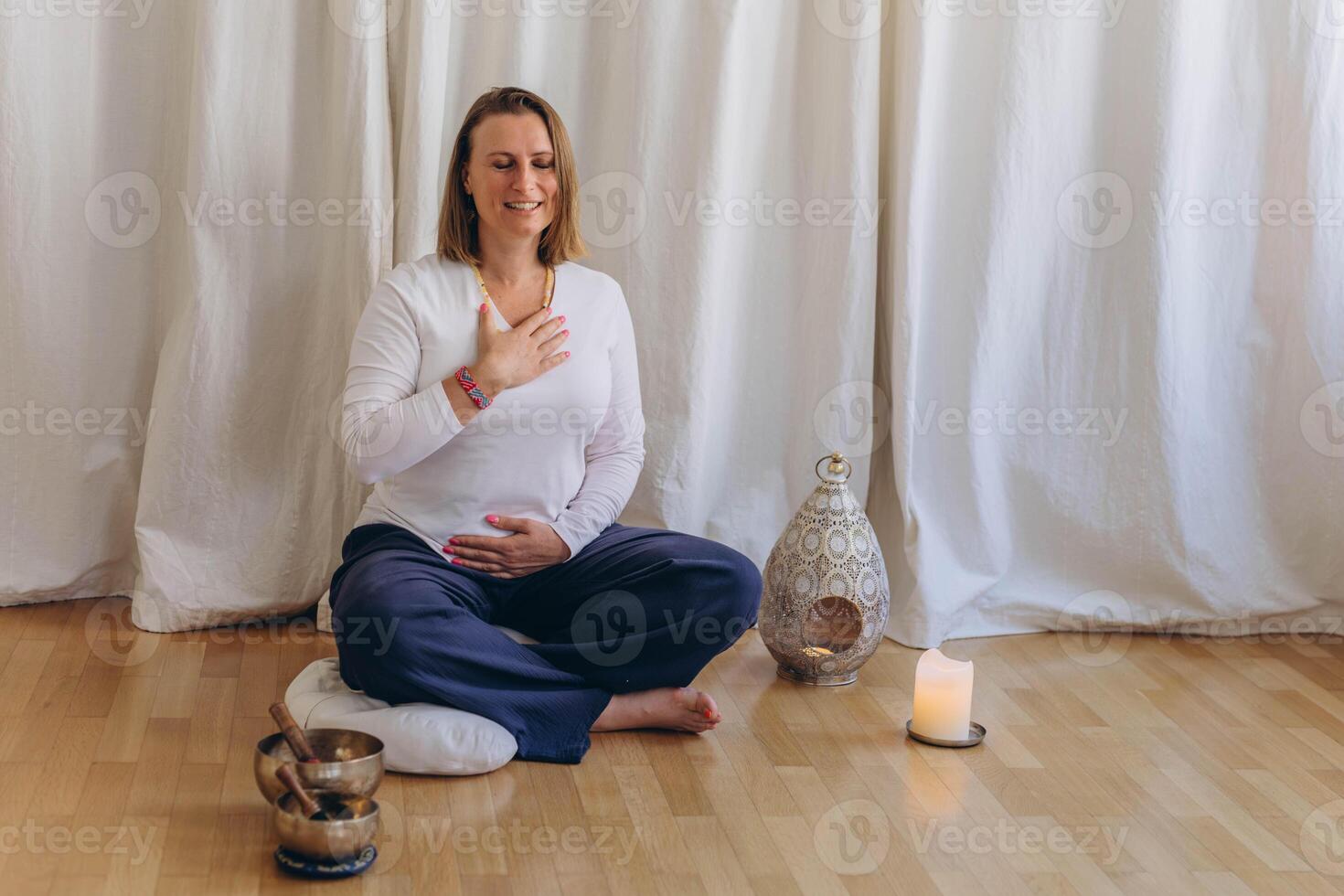 A woman sits on the floor with her eyes closed, practicing deep breathing exercises. She inhales and exhales slowly photo
