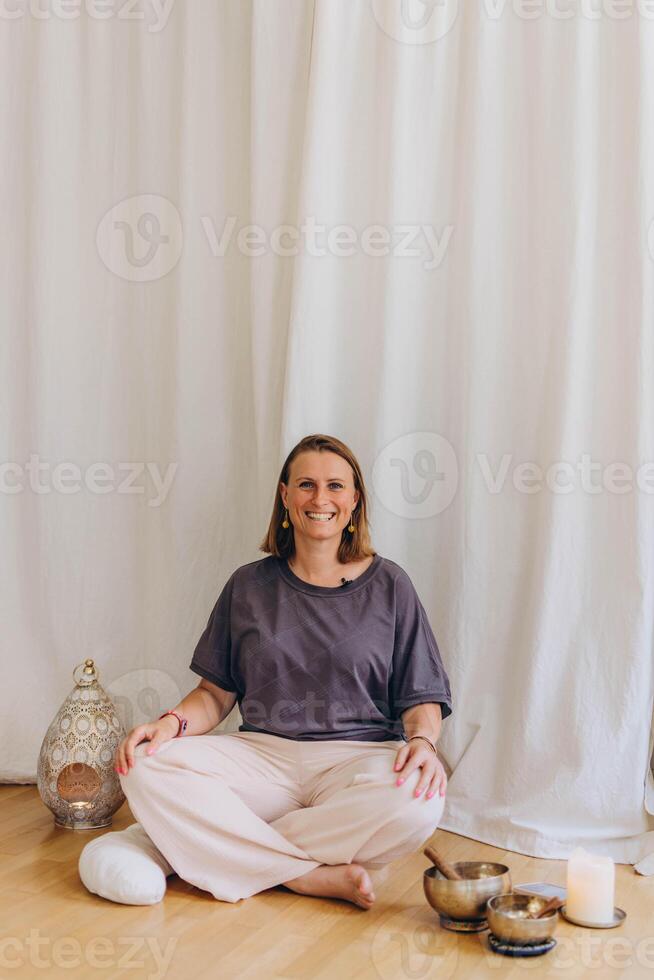 A woman sits on the floor with her eyes closed, practicing deep breathing exercises. She inhales and exhales slowly photo
