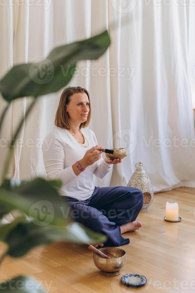 Young woman playing on a singing tibetian bowl.Relaxation and meditation.Sound therapy,alternative medicine. photo