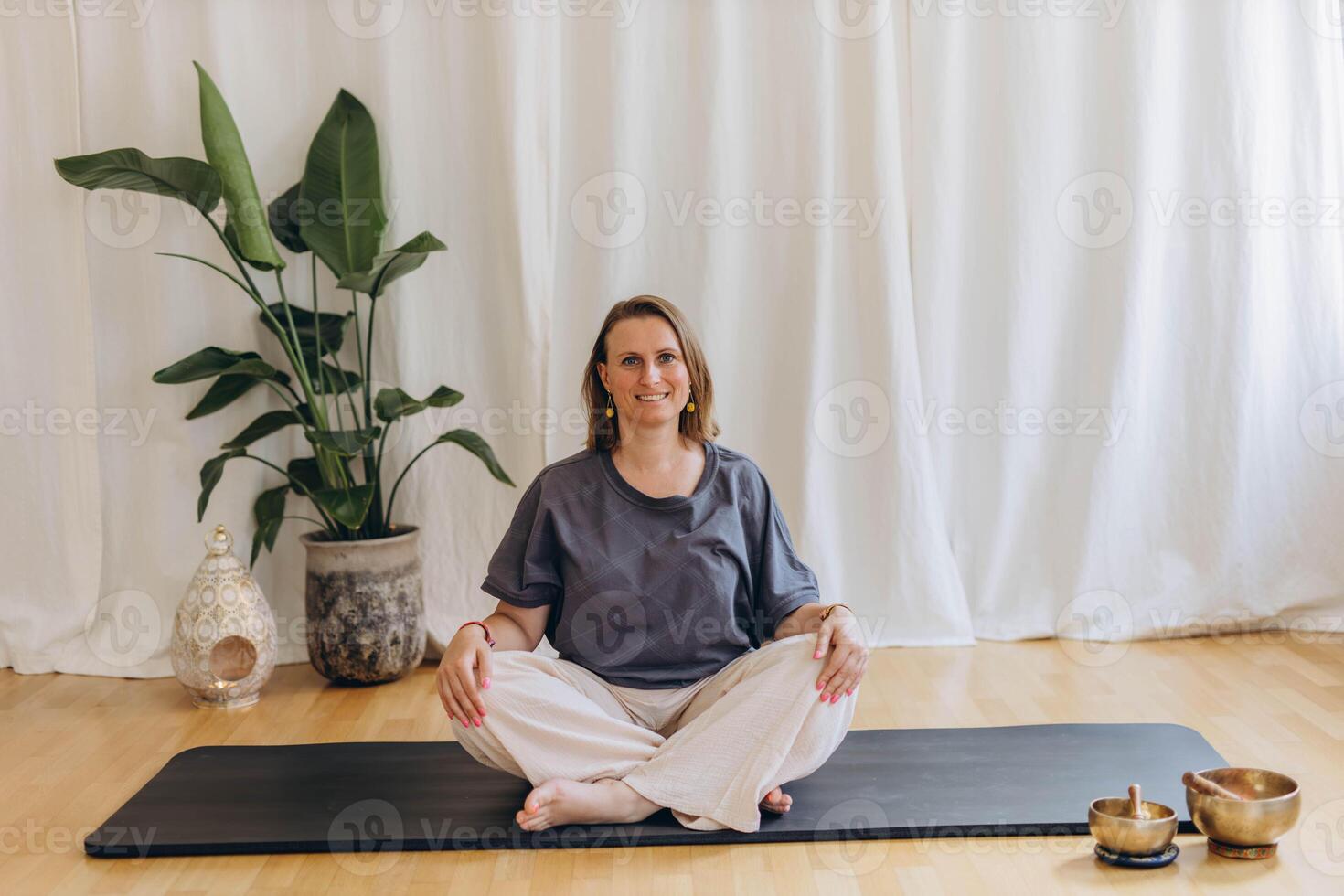 A woman sits on the floor with her eyes closed, practicing deep breathing exercises. She inhales and exhales slowly photo