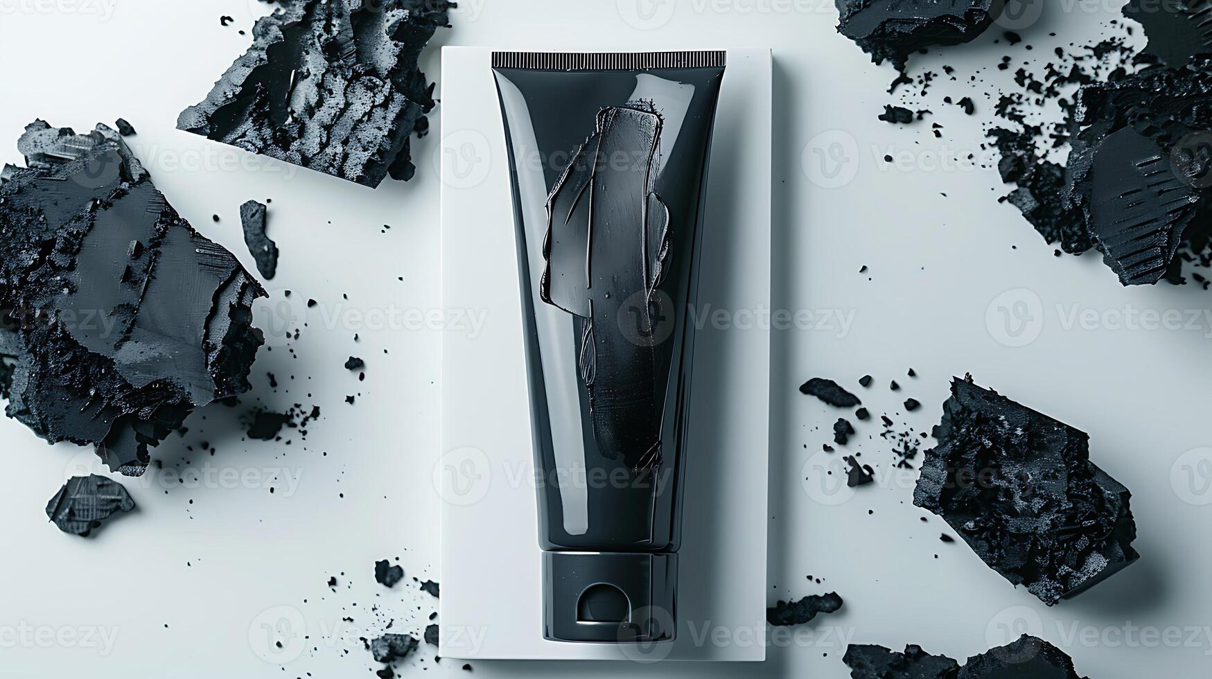 activated charcoal face mask tube with charcoal pieces on white background for skincare routine. photo