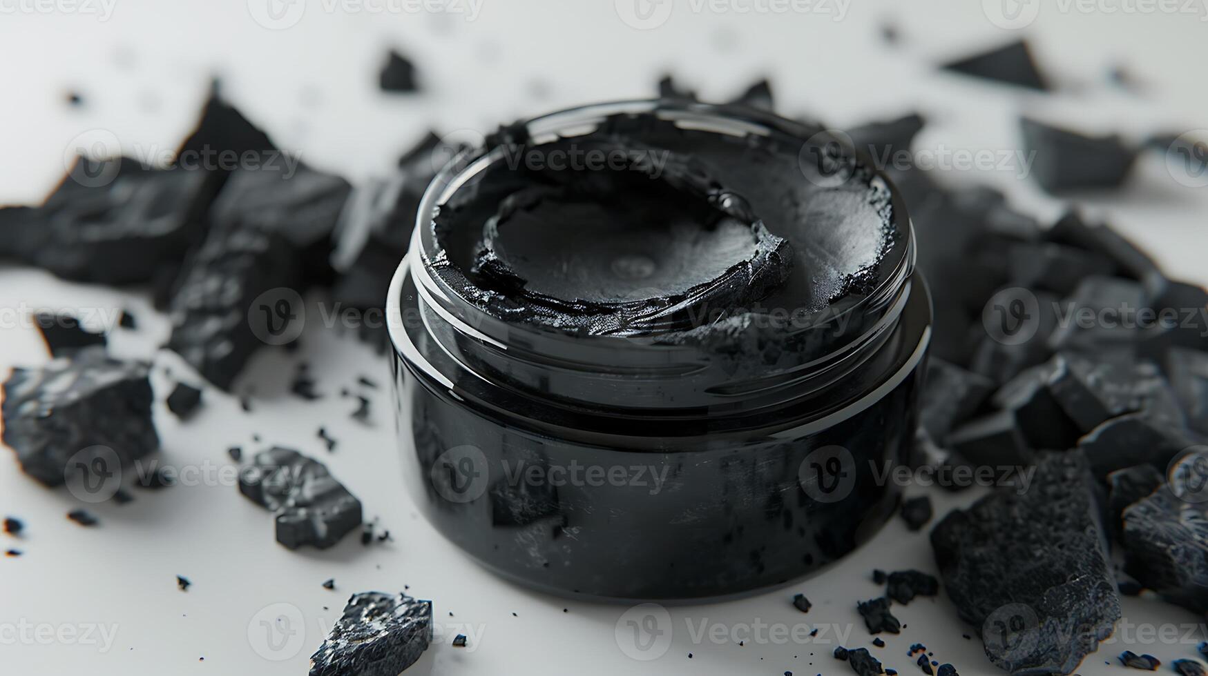 activated charcoal face mask in a jar on a plain white background with charcoal pieces. photo
