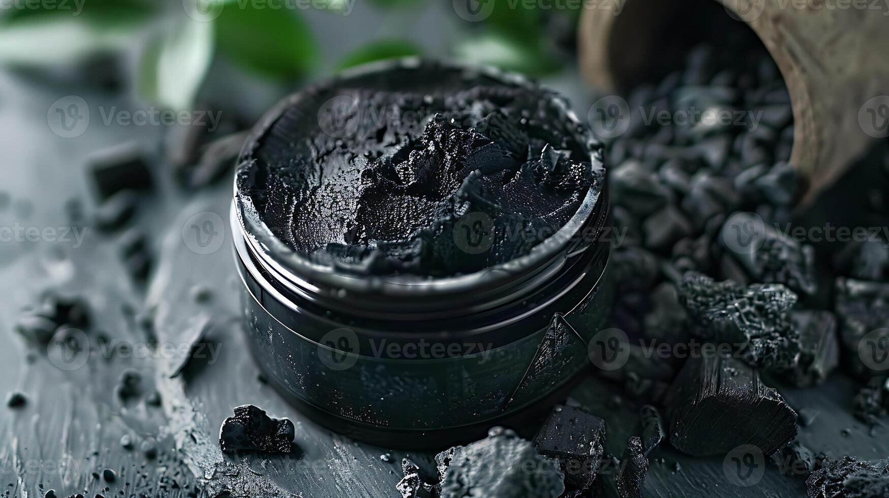 activated charcoal facial scrub container with charcoal pieces on tabletop in bright room setting photo