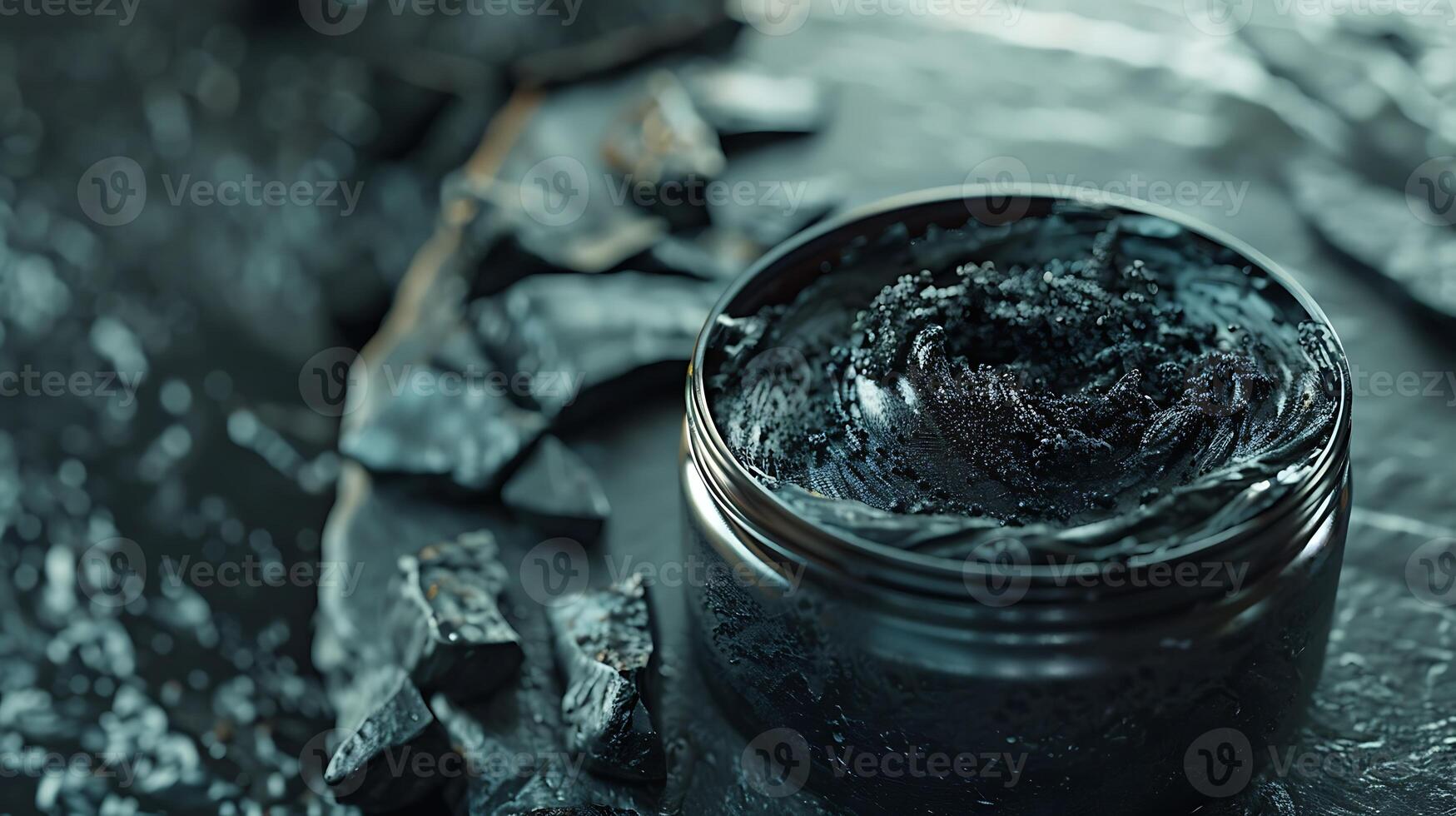 activated charcoal body scrub jar displayed on table with charcoal pieces photo