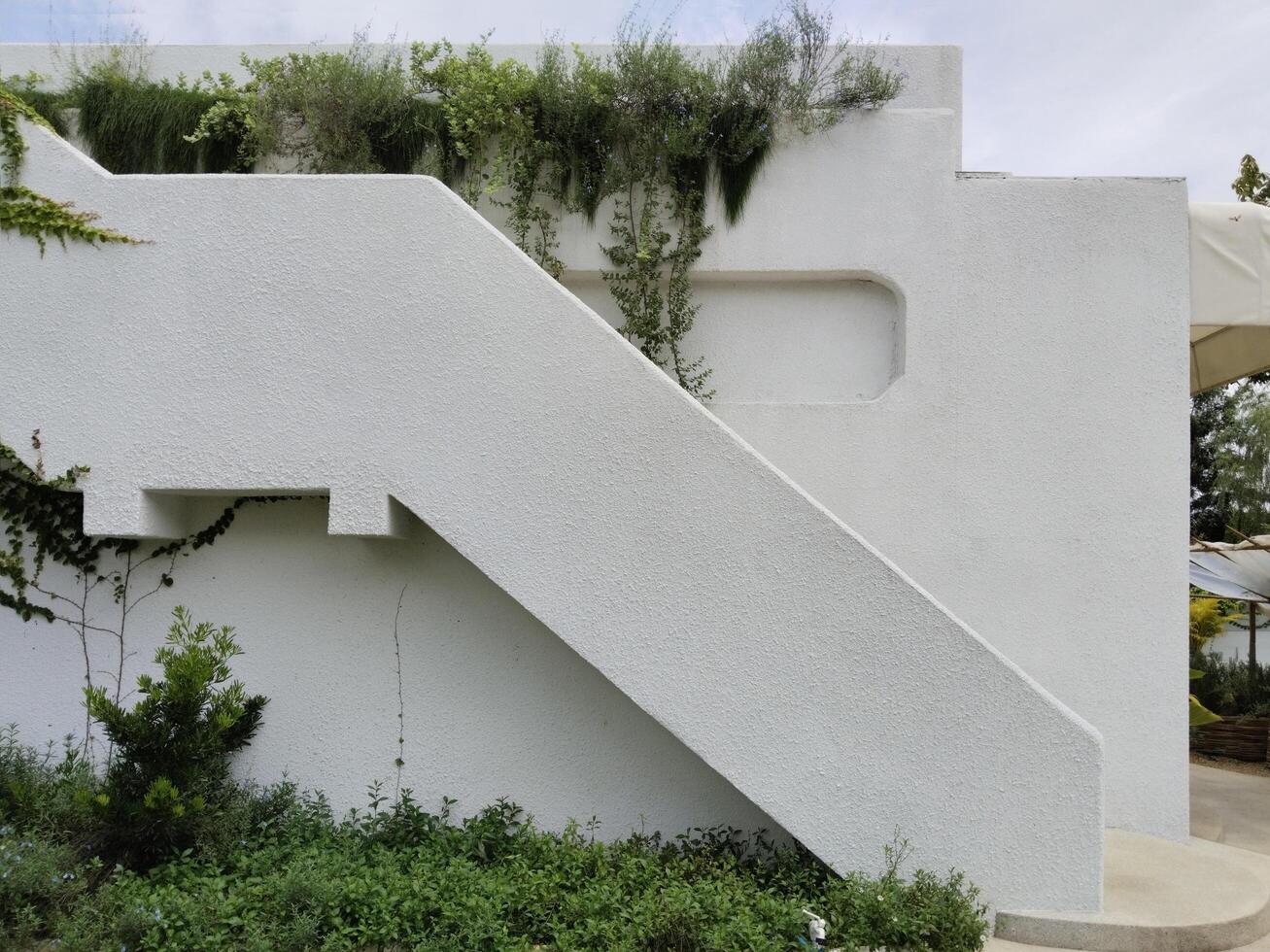 A white house with a flower-filled balcony in a garden on a sunny summer day photo
