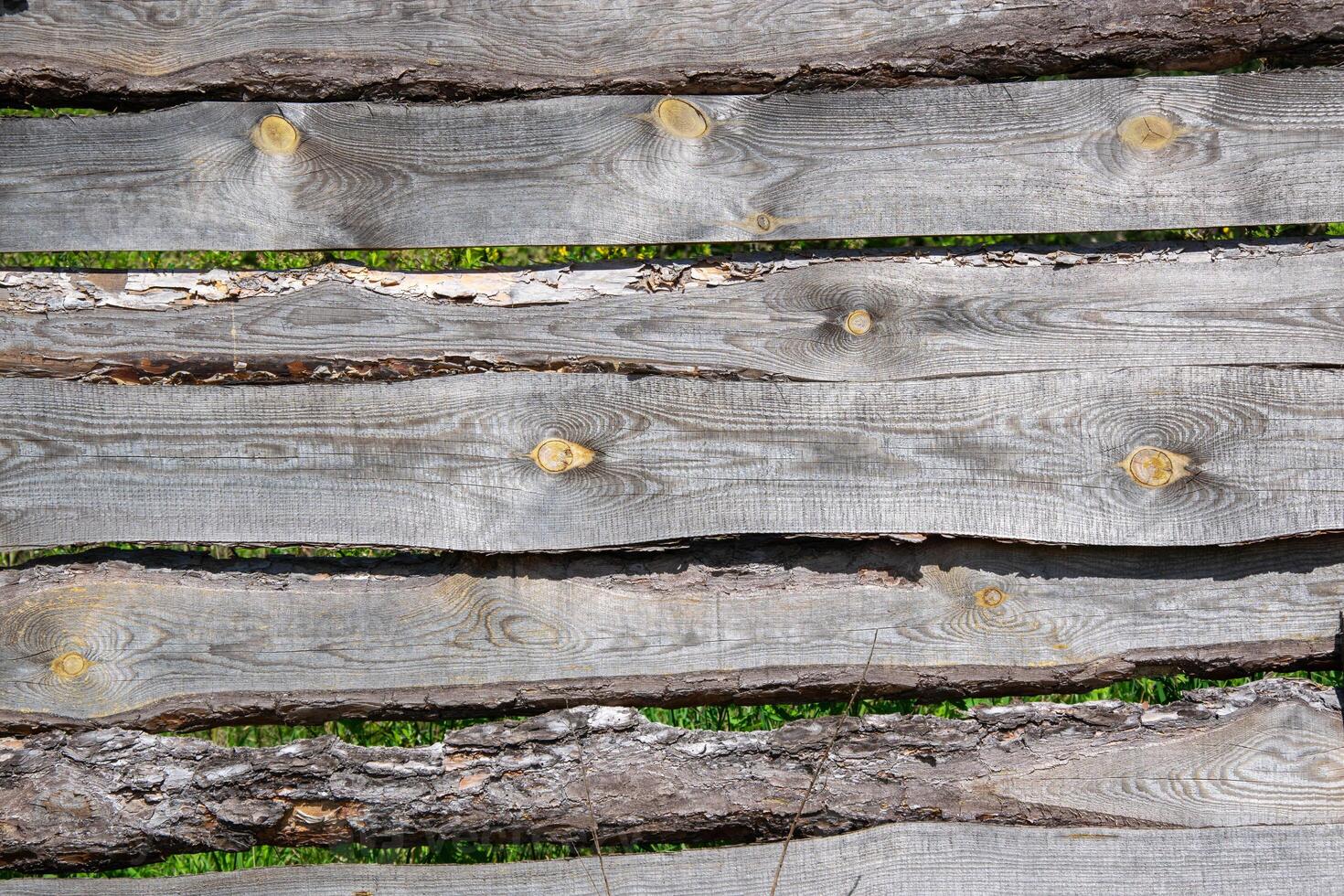 A close up image of several weathered wood panels making up a fence, with visible knots photo