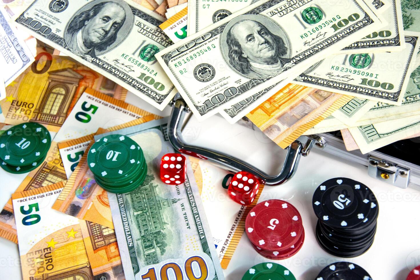A close-up image of various poker chips, dice, and US dollar bills and Euro banknotes scattered on a white surface photo