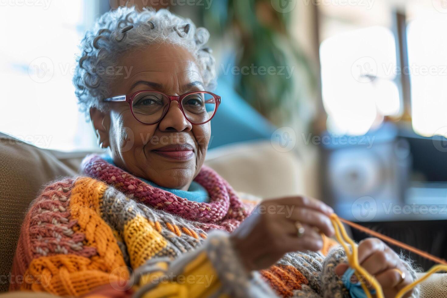 A black woman in her 70s enjoys knitting and watching TV in her cozy living room photo