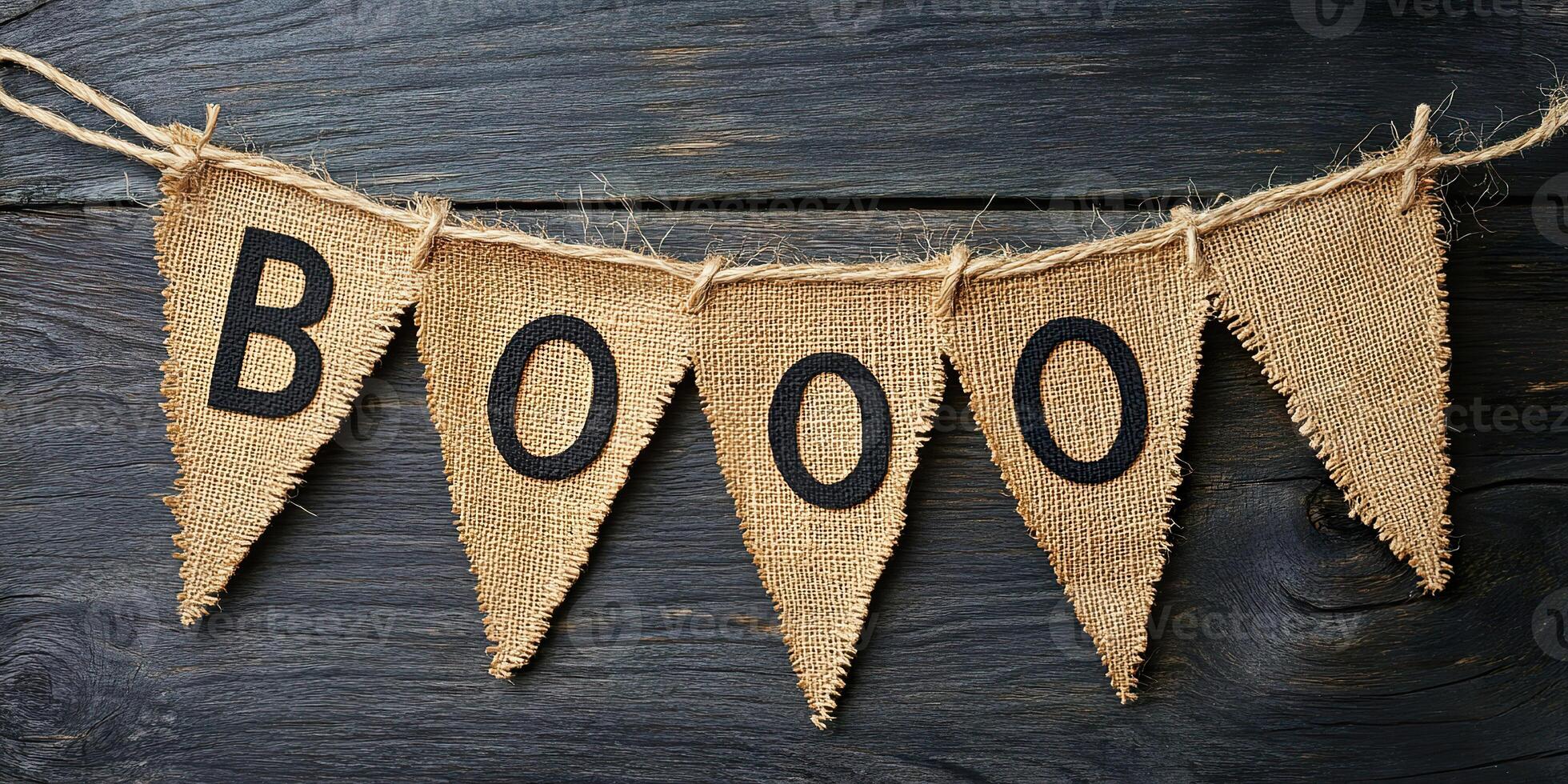 A burlap banner with the word Boo hangs on a wooden surface photo