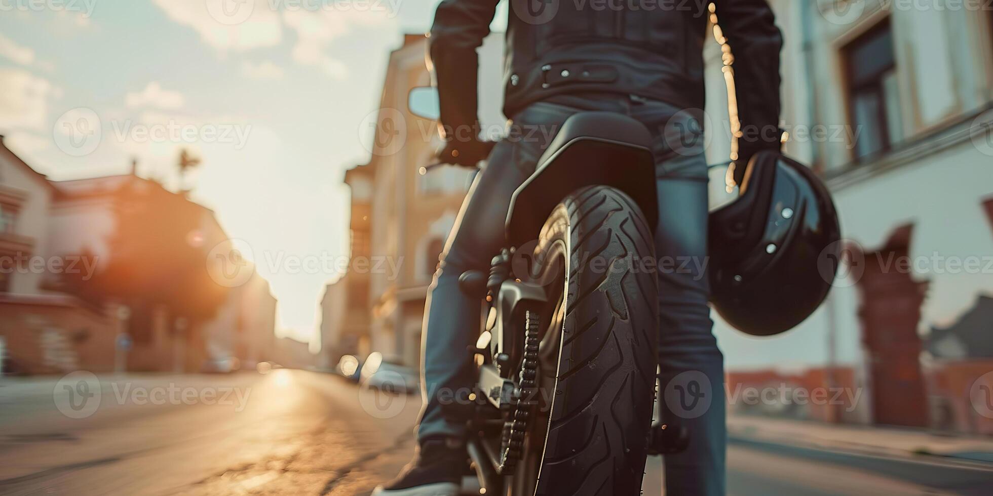 Biker stands with helmet in hand next to motorcycle during sunset in city photo