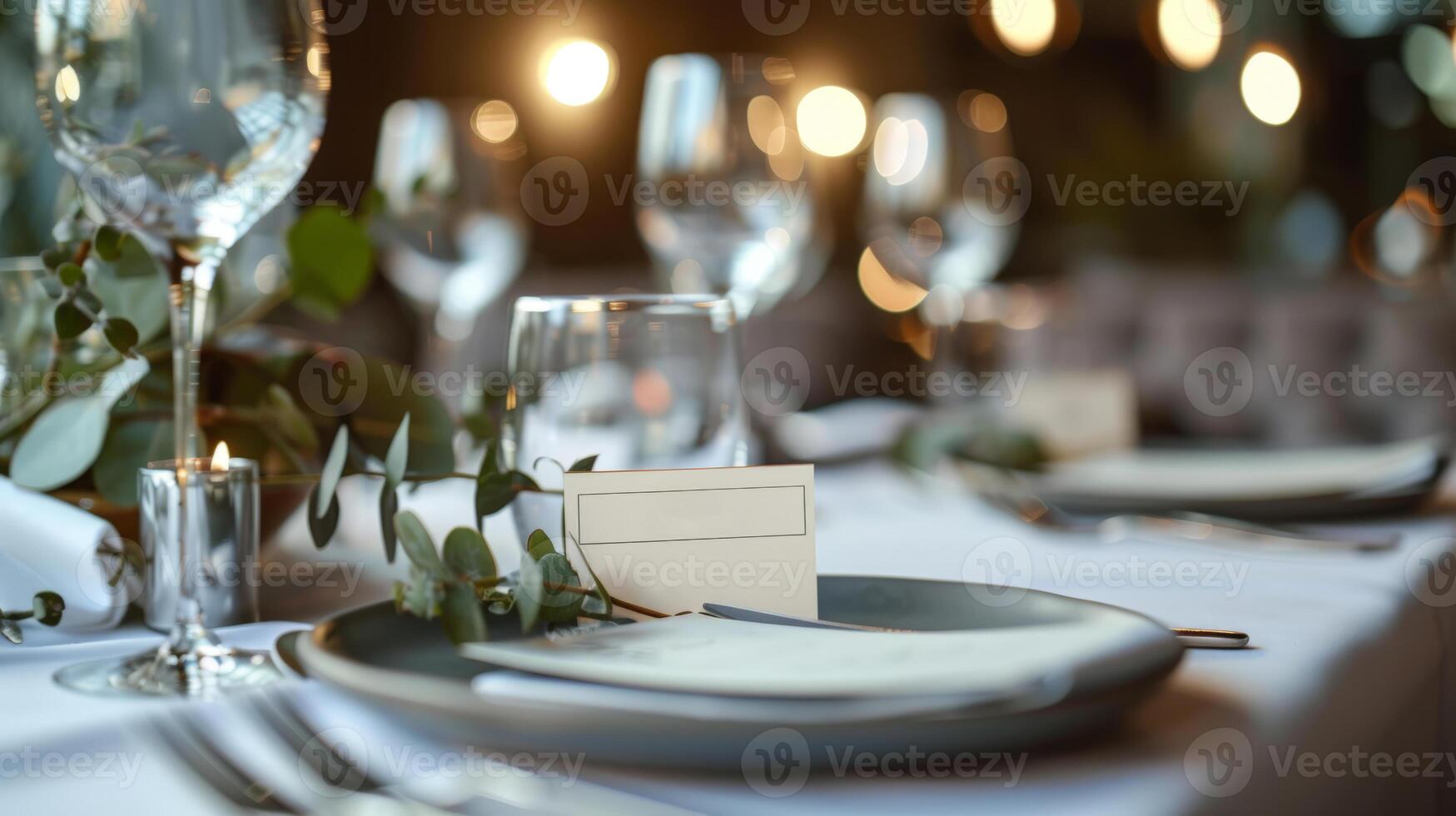 An elegantly arranged table featuring fine glassware and delicate greenery invites guests to an intimate dining experience, illuminated by warm ambient lights creating a cozy atmosphere photo