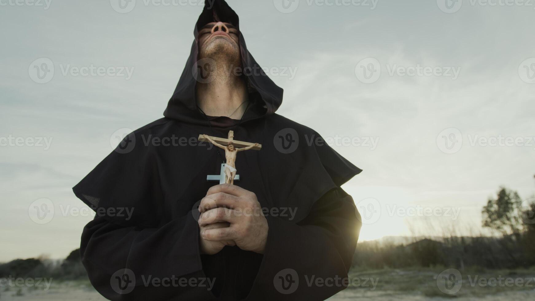 Religious Monk Prays With A Crucifix Of Jesus In His Hand Kneeling On The Sand photo