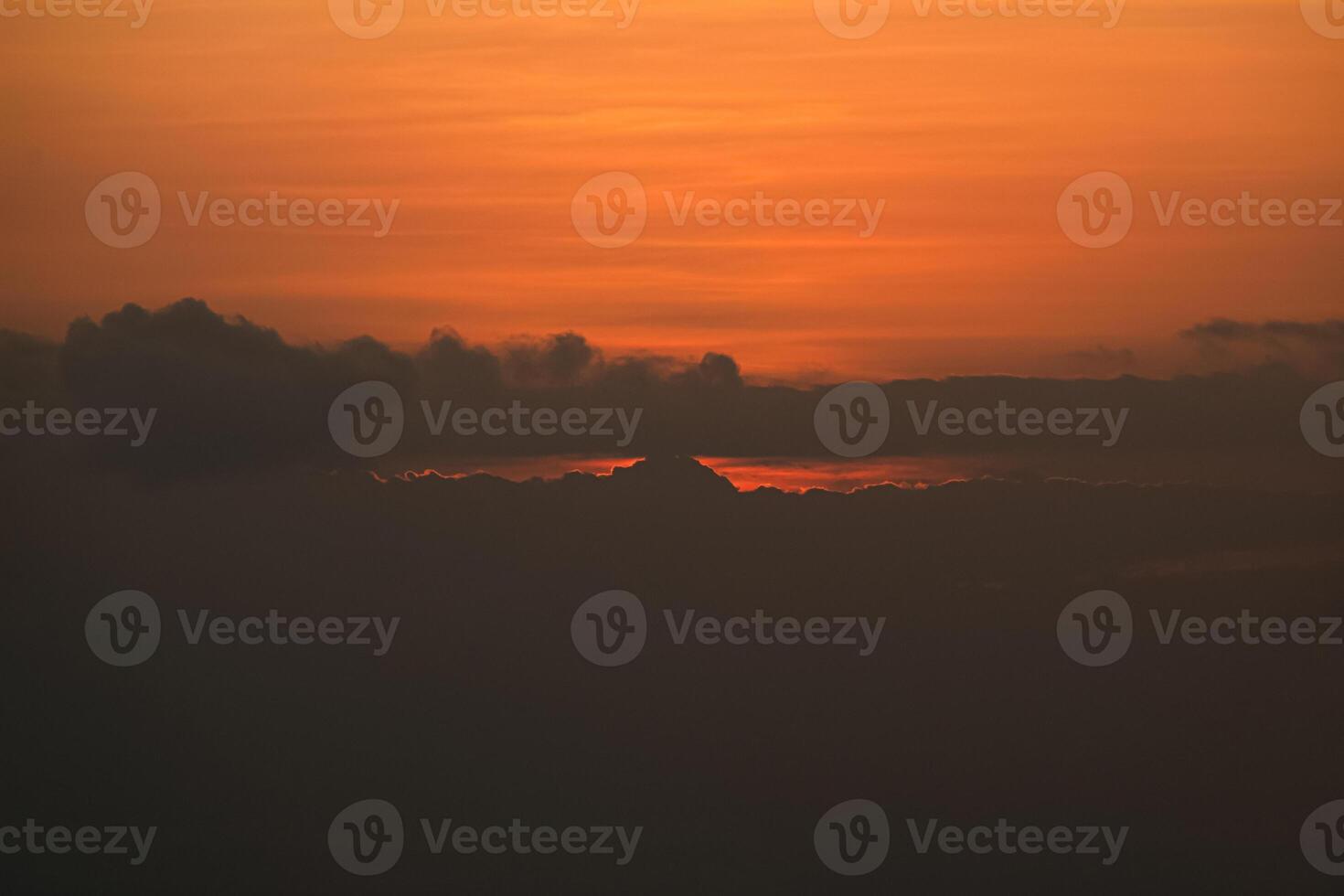 Sunset behind clouds and silhouetted hills photo