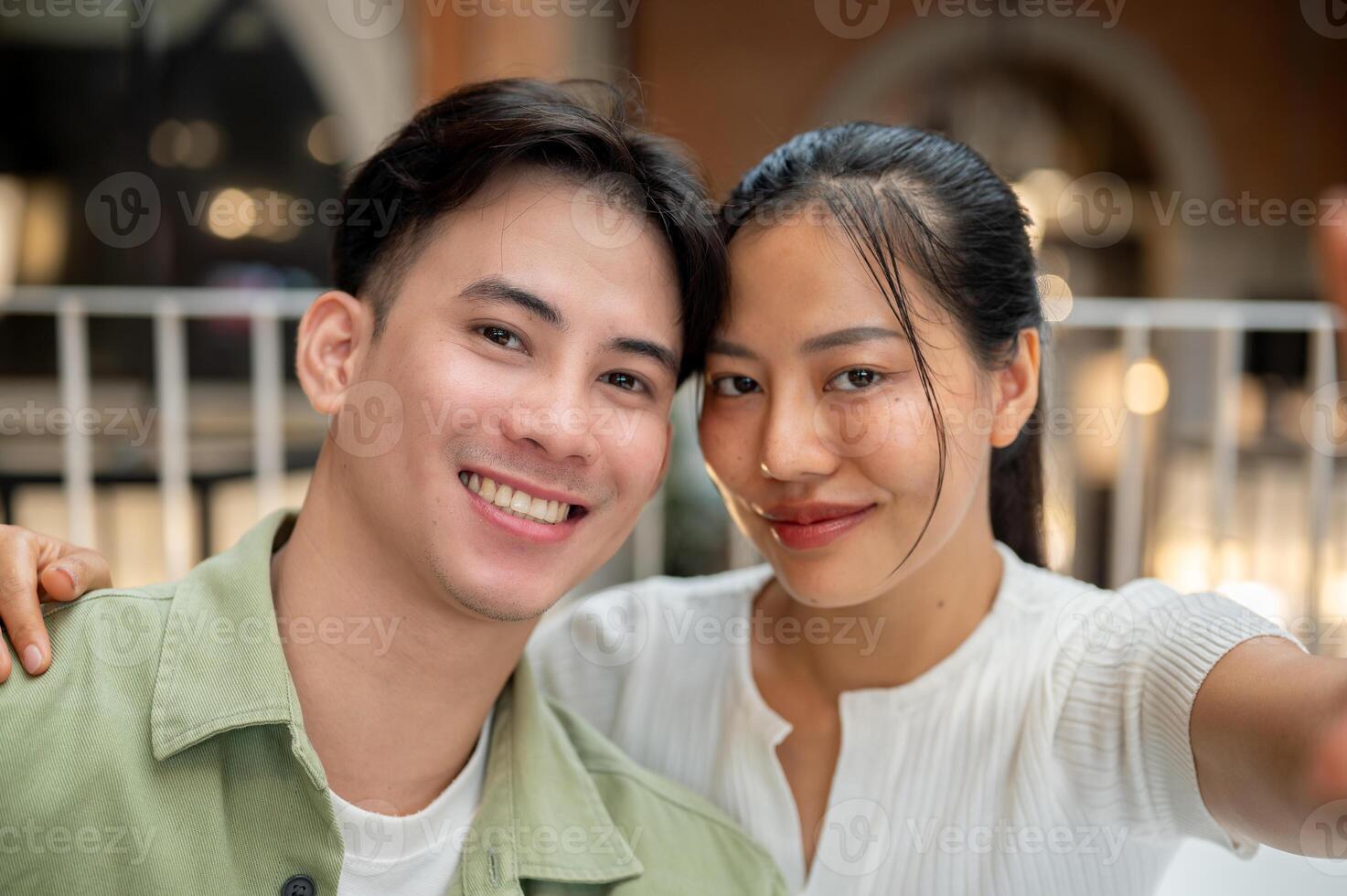 A lovely, happy young Asian couple is taking a selfie together while on a date at a coffee shop. photo