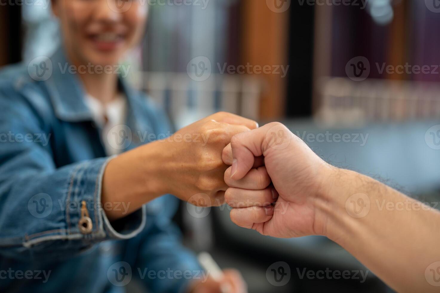 A close-up of two people giving each other a fist bump during a meeting at a coffee shop. photo