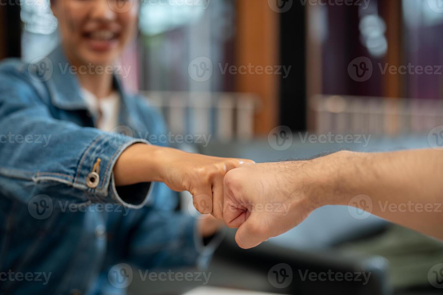 A close-up of two people giving each other a fist bump during a meeting at a coffee shop. photo