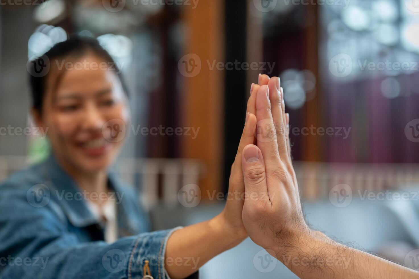 A close-up of two people giving each other a high five during a meeting at a coffee shop. photo