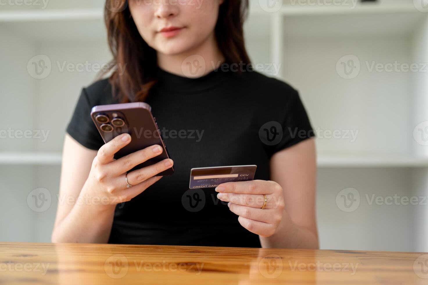 A cropped image of a woman holding a smartphone and a credit card, using a mobile banking app. photo