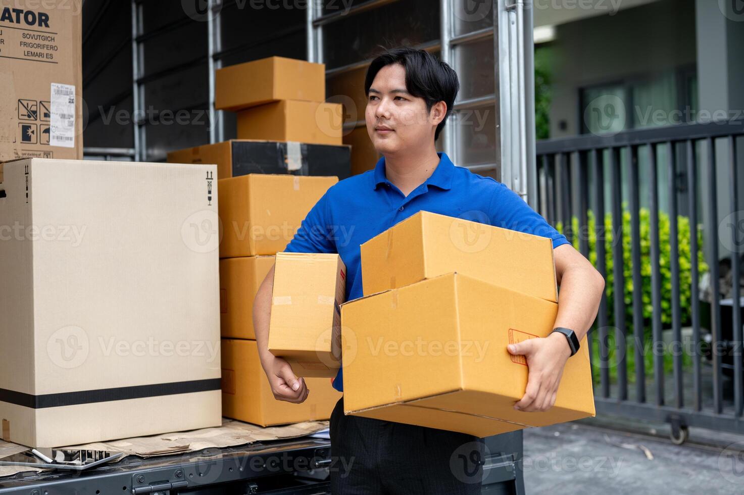 A delivery guy is carrying boxes from his truck to deliver to a customer in front of their house. photo