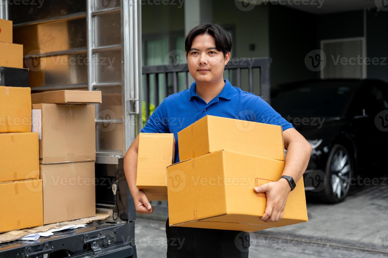 A delivery guy is carrying boxes from his truck to deliver to a customer in front of their house. photo