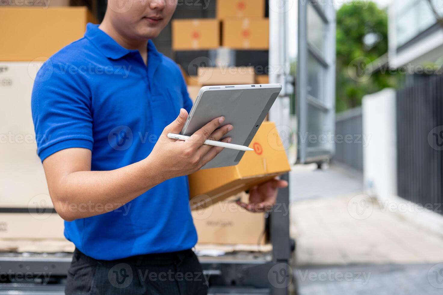 A delivery guy checking the address on his tablet while carrying a package for delivery. photo