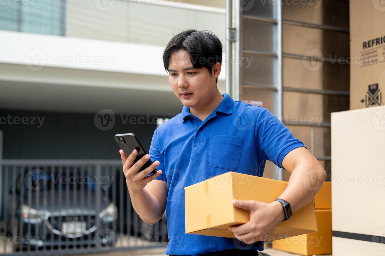 An Asian delivery guy is checking a customer's address on his smartphone before making the delivery. photo