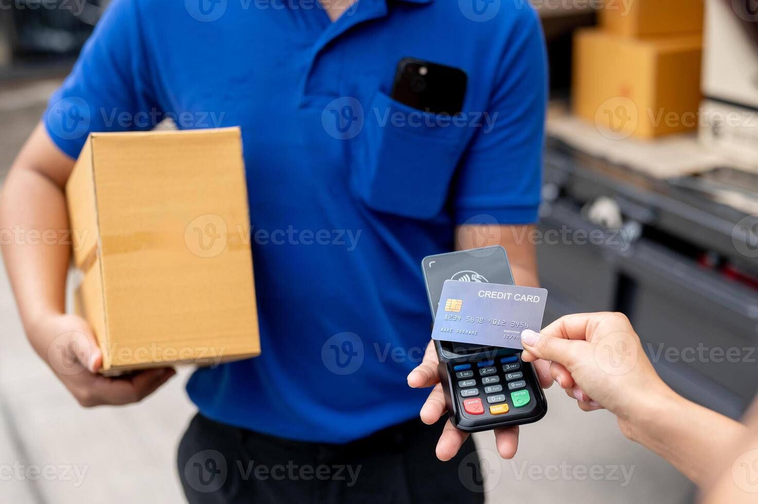 A customer tapping her credit card on a card reader before receiving a package from a delivery man. photo