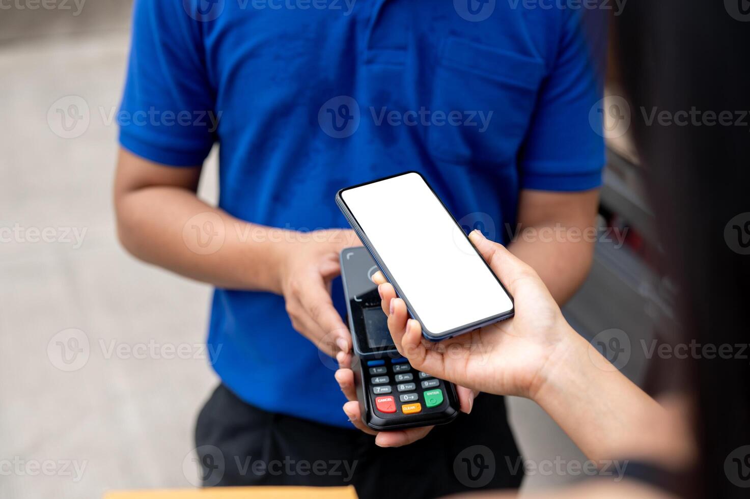 A customer tapping her smartphone on a card reader before receiving a package from a delivery man. photo