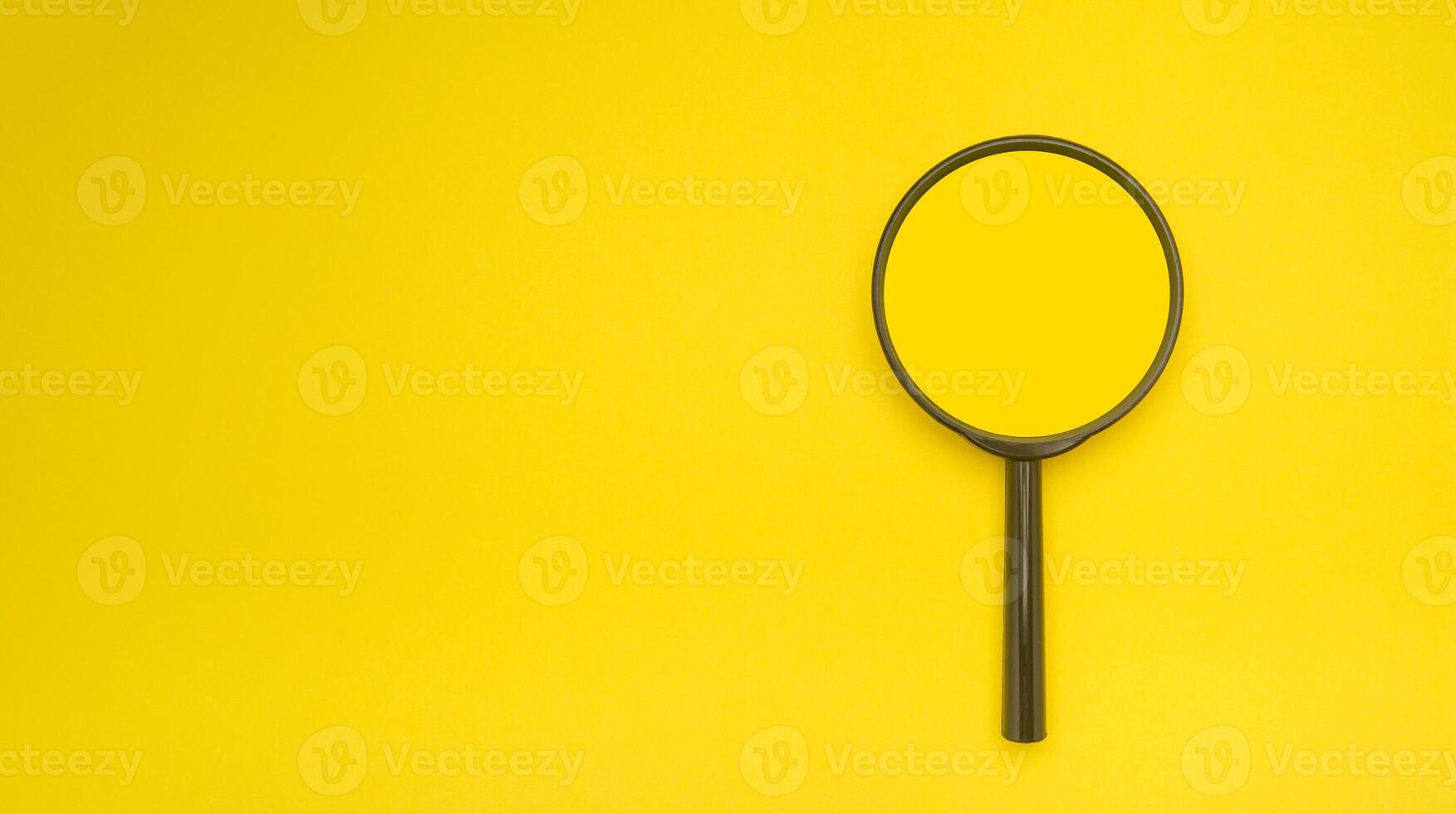 Overhead view of a magnifying glass isolated on a yellow background photo