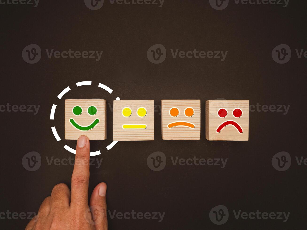 Overhead view of hand push green smiley face emoticon on the wooden cube over a black background photo