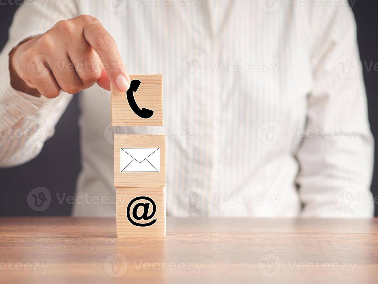Contacts us. Hand holding a wooden cube with icon symbol telephone, email, address photo