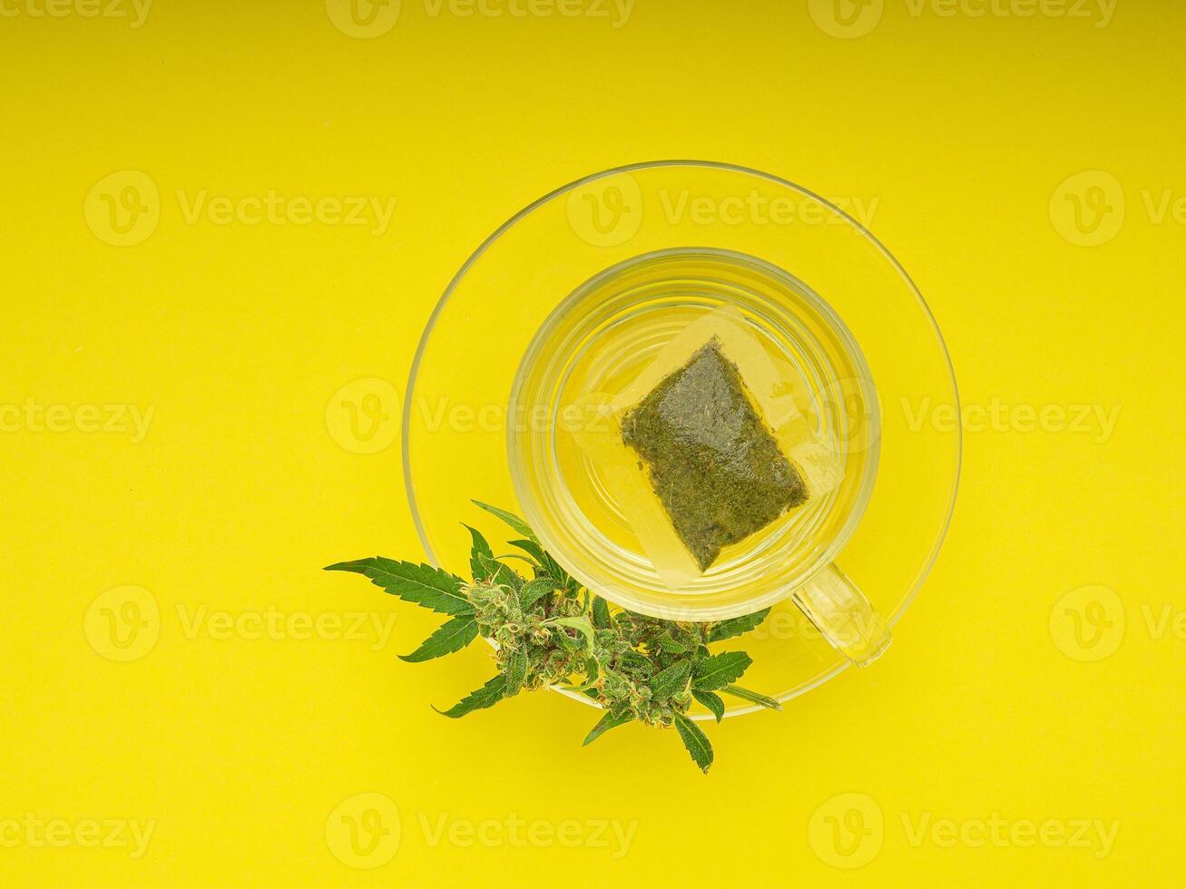Top view of cannabis tea in a teacup and marijuana buds flower isolated on a yellow background photo