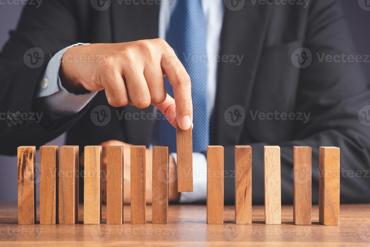 Business and risk management. A businessman pick up a wooden block while sitting in the office photo