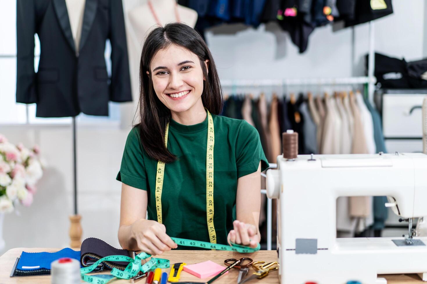 Smiling Caucasian female fashion designer works in studio choosing colorful fabric for a dress design collection and looking at camera , choose clothing colors for tailoring and designing photo