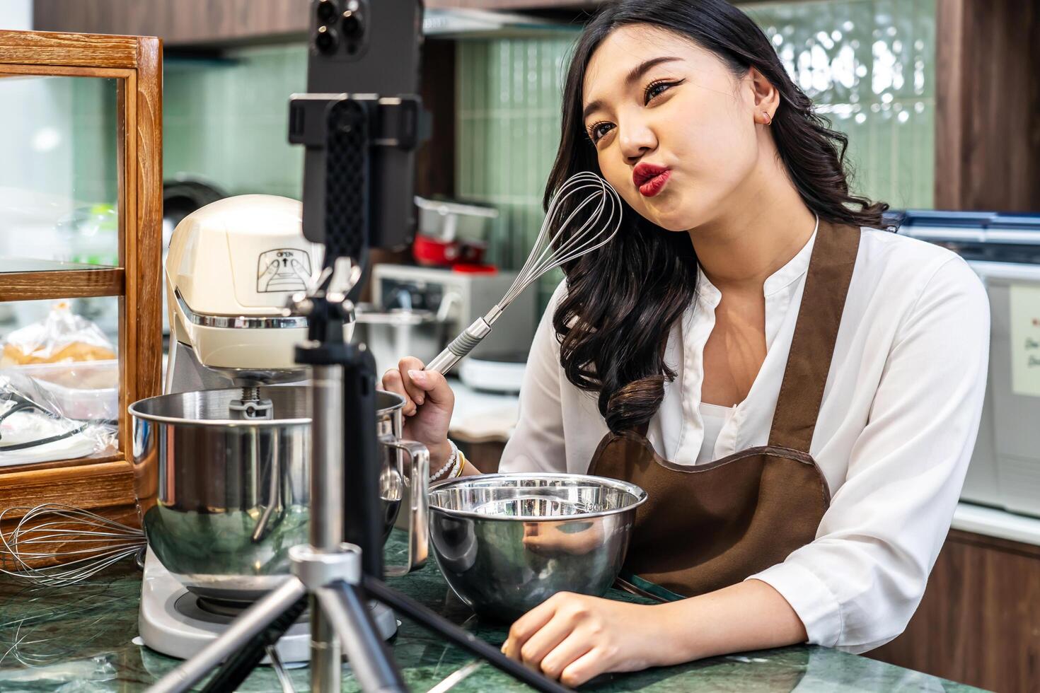 Young asian women is shop owner Put on an apron making cream for cupcakes, Using electric mixer, Preparing Cookies, Cooking, Homemade, Made specifically to sell, and recording for food blog photo