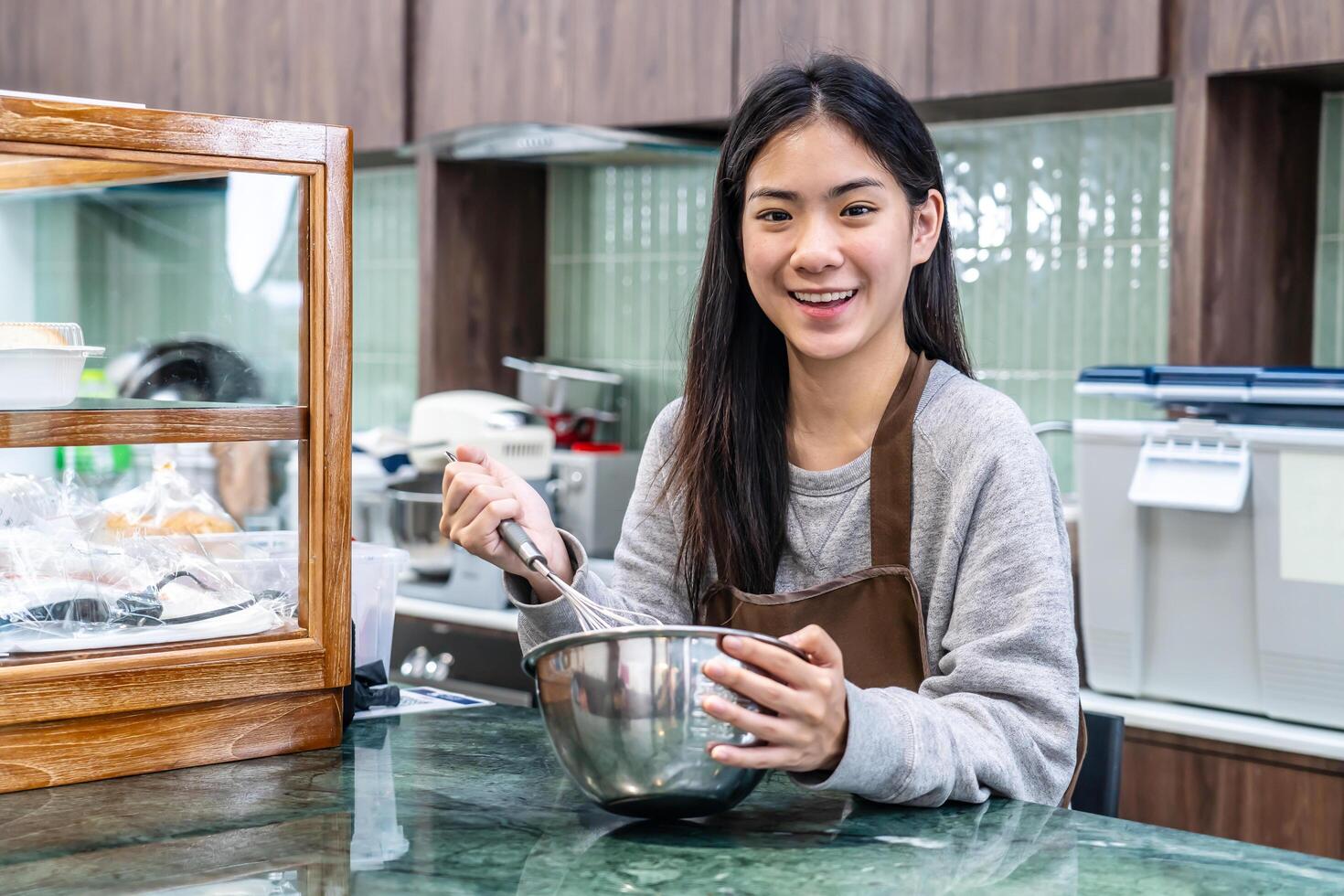 Young asian women is shop owner Put on an apron making cream for cupcakes, Using electric mixer, Preparing Cookies, Cooking, Homemade, Made specifically to sell photo