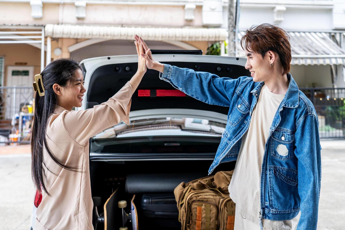 Happy asian young couple holding hands, standing against the background of a white car with Luggage for outdoor recreation, Concept of the man and woman is ready for travel. photo