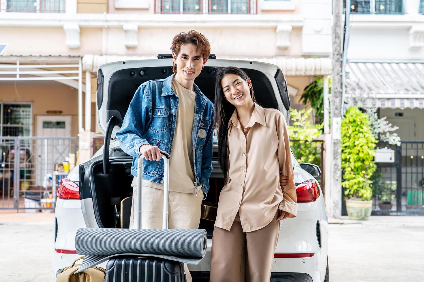 Couple young asian man and woman tourist standing behind the trunk of car, loading a car for a sstkroadtrip. Travel. Summer adventure photo