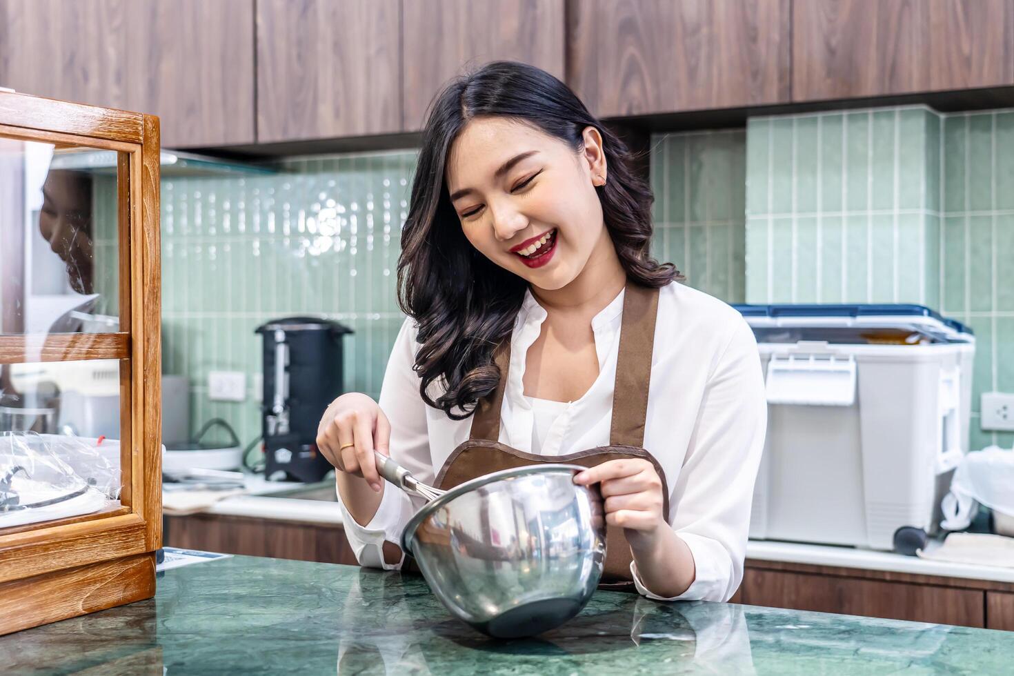 Young asian women is shop owner Put on an apron making cream for cupcakes, Using electric mixer, Preparing Cookies, Cooking, Homemade, Made specifically to sell photo